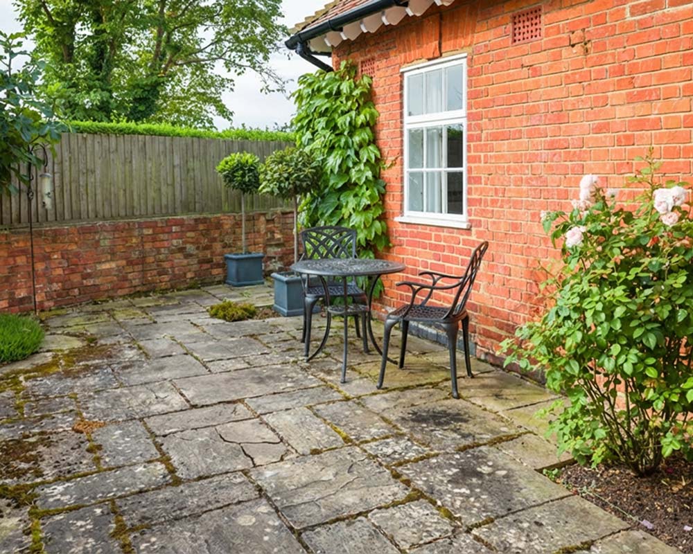 Verwitterte Naturstein-Terrasse mit Sitzplatz im Gartenbereich